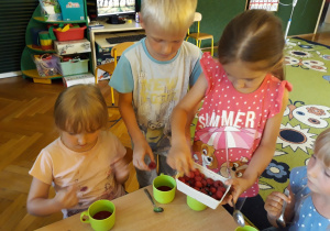Dzieci jedzą mus truskawkowy z dodatkiem malin.