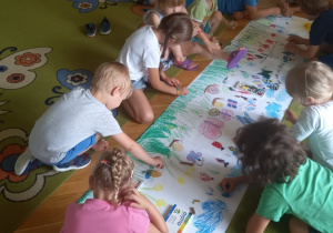Dzieci maliją łąkę na dużym arkuszu papieru.