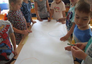 Dzieci rysują koła na dużym arkuszu papieru.