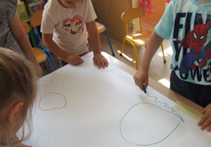 Dzieci rysują fale na papierze.