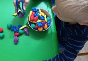 Dziecko manipuluje owocami z gumy.