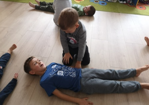 Chłopiec przesuwa chłopca leżącego na podłodze
