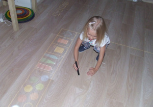 Dziewczynka rysuje za pomocą podłogi interaktywnej.