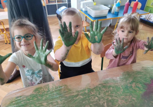 Dzieci pokazują rączki pomalowane zieloną farbą.