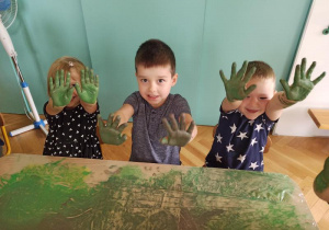 Dzieci pokazują rączki pomalowane zieloną farbą.