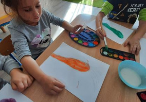Dziewczynka maluje po lukrze farbą.
