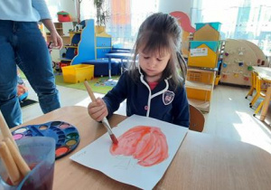 Dziewczynka maluje swoje warzywo.