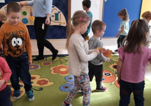 Dzieci tańczą z liśćmi do piosenki.