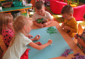 Dzieci naklejają wydarty papier.