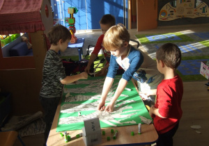 Dzieci przyklejają wydarte framenty gałęzi brzozy.