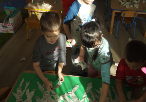 Dzieci przyklejają wydarte framenty gałęzi brzozy.