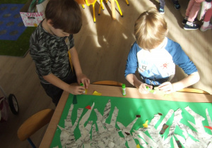 Dzieci przyklejąją liście z papieru.