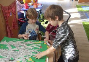 Dzieci przyklejąją liście z papieru.