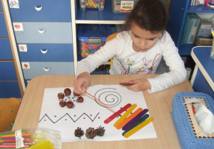 Dziewczynka układa materiał przyrodniczy na graficznej ilustracji.