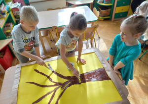 Dzieci malują pień drzewa