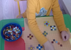 Chłopiec tworzy kompozycję z ceramicznej mozaiki