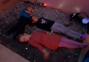 Dzieci leżą na podświetlanym dywanie.