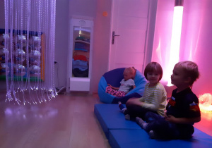 Dzieci w pozycji siedzącej wykonują ćwiczenia oddechowe.