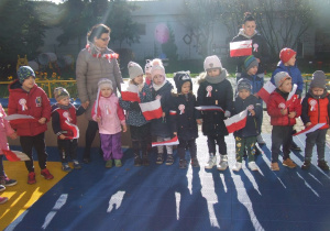 Dzieci stoją z flagami na tarasie.