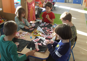 Dzieci wyklejają kartki.