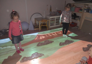 Dziewczynki grają w grę na podłodze interaktywnej.