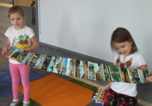 Dziewczynki pokazują pocztówki z Włoch.