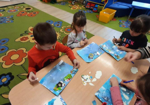 Dzieci na kartcę układaja szablony chmurek i kropel deszczu.