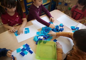 Dzieci na białej kartce układają bibułę.