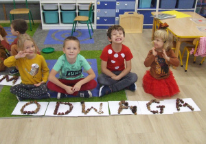 Dzieci siedzą przy ułożonym napisie.