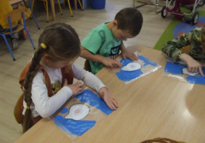 Dzieci rozprowadzają farbę znajdującą się w foliowej koszulce.