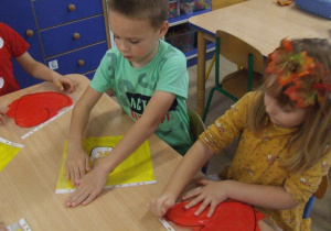 .Dzieci rozprowadzają farbę znajdującą się w foliowej koszulce.
