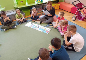 Dzieci słuchają legendy czytanej przez nauczycielkę.