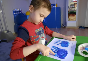 Chłopiec maluje palcami chmurkę.