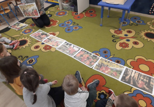 Dzieci ogladają wszystkie ilustracje opowiadania o wiewiórkach z polany.