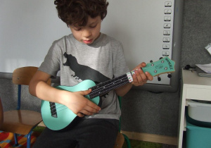Chłopiec gra na ukulele.