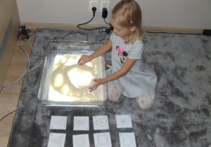 Dziewczynka rysuje wzory na kaszy mannie.