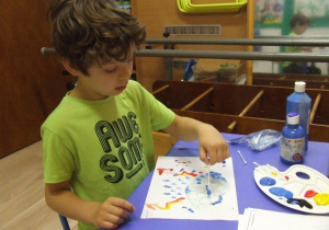 Chłopiec maluje patyczkami higienicznymi.