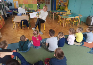 Dzieci słuchają bajki czytanej przez nauczycielkę.