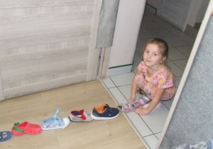 Dziewczynka układa swój but na początku rzędu bucików.
