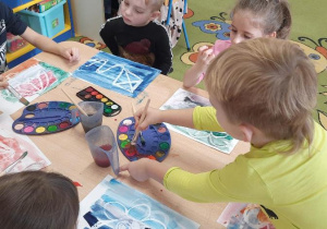 Dzieci malują farbami swoje obrazki.
