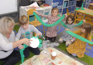 Dzieci pokazują gotowe elementy do ozdobienia choinki.