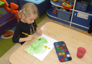 Dziewczynka maluje farbami.