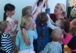 Dzieci oglądają pacynkę trzymaną przez aktorkę.