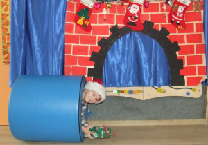 Chłopiec w stroju Mikołaja wychodzi z tunelu.
