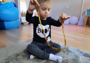 Chłopiec pokazuje swój łańcuch z makaronu.