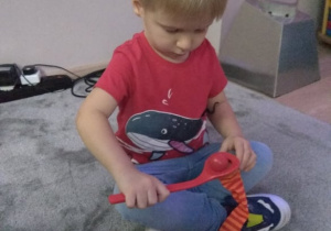 Chłopiec wkłada łopatką piłkę do woreczka.