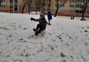 Chłopiec zjeżdża na sankach z zaśnieżonej górki.