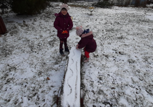 Dziewczynki bawią się śniegiem.