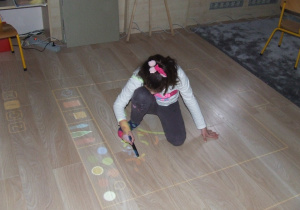 Dziewczynka rysuje z wykorzystaniem podłogi interaktywnej.