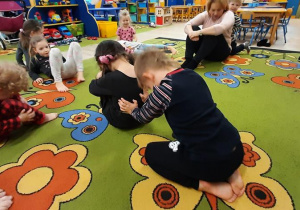 Zabawa "Kamień"- dzieci próbują przepchnąć kolegę, siedzącego na dywanie.